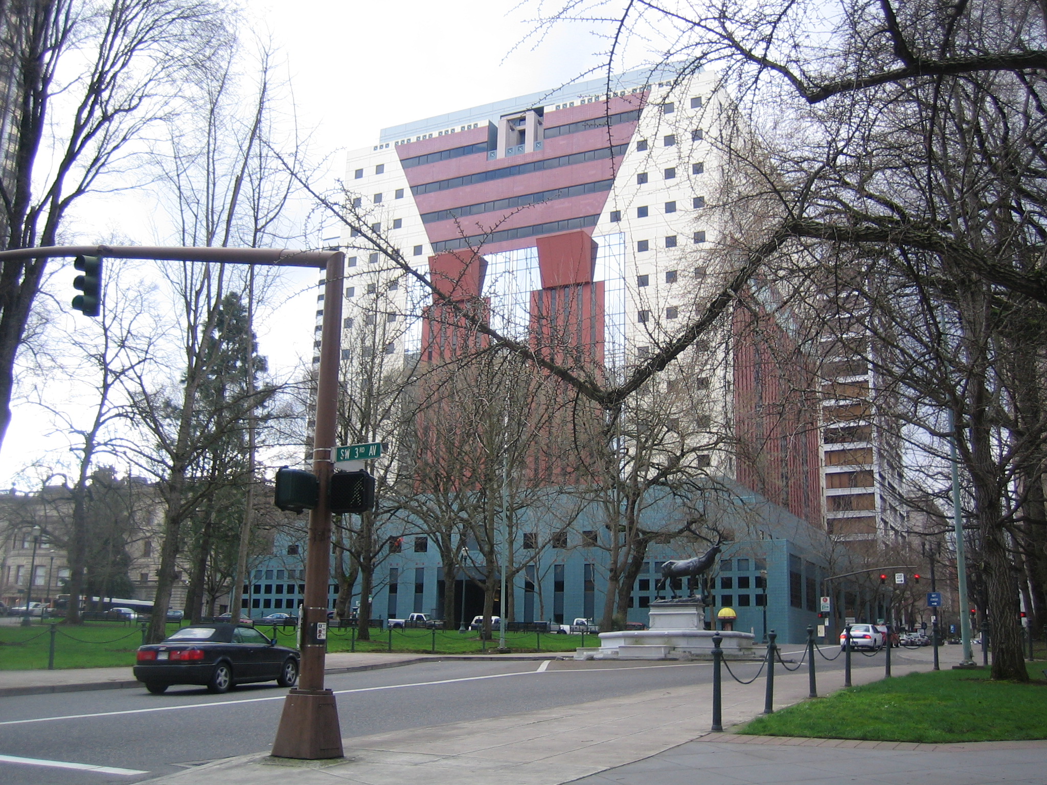 The Portland Building in Portland, Oregon, showing its teal-tiled two-story podium and the tan and maroon-striped facade with stylized column and keystone motifs above