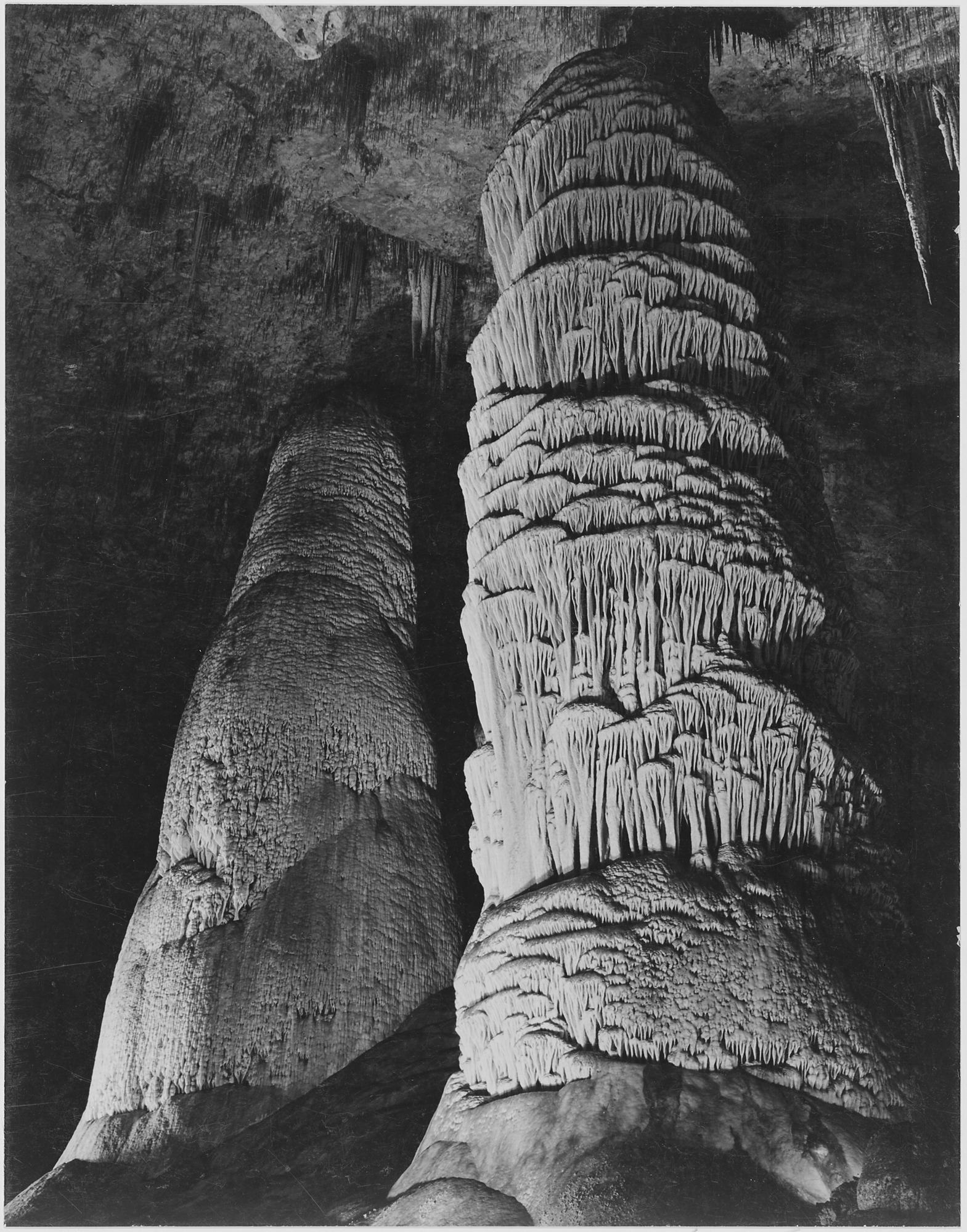 A black-and-white archival photograph of the Giant Dome, a large stalagmite column in the Hall of Giants section of the Big Room at Carlsbad Caverns National Park, New Mexico