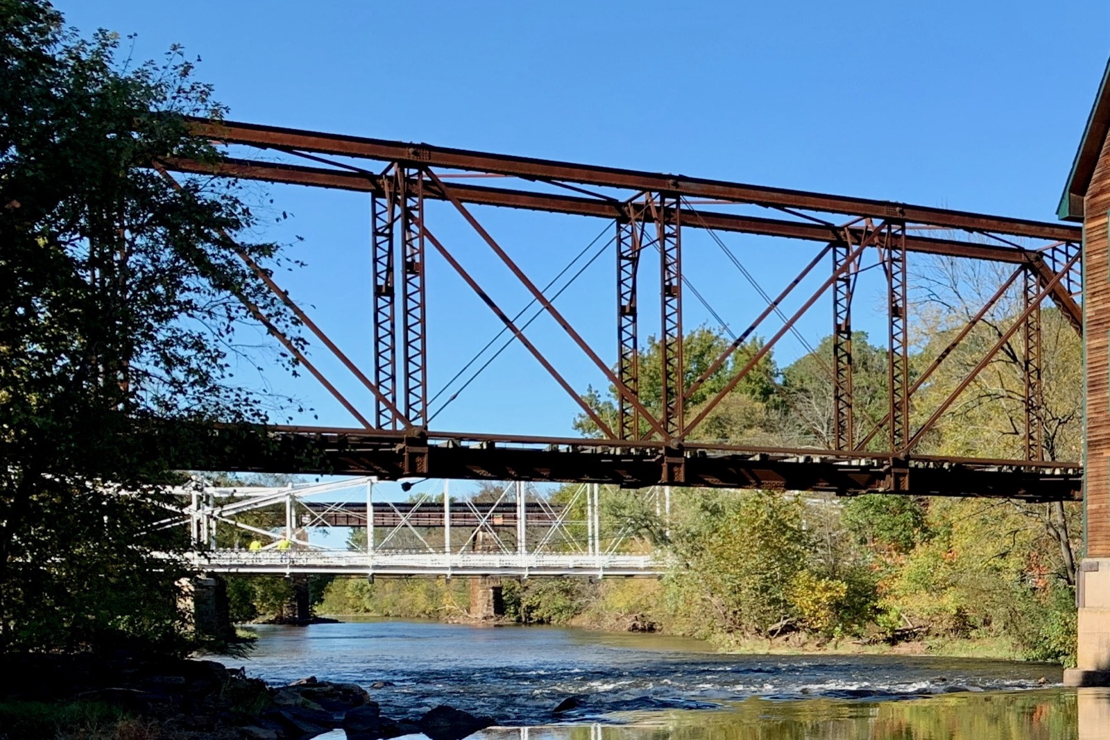 A steel through Pratt truss bridge, a former New Jersey Central Railroad crossing at Neshanic Station, showing the triangular web of diagonal and vertical members between the parallel top and bottom chords